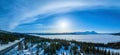 Wide scenic panorama on frozen lake Rossvatnet or Reevhtse, mountains, forest, sunny blue sky. Scandinavian white winter landscape