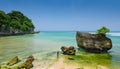 A wide-screen view of a girl standing in the water at padang padang beach in bali