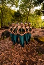 a wide shot of an Asian woman standing together in the forest while wearing a green dance costume with dead leaves Royalty Free Stock Photo