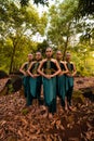 a wide shot of an Asian woman standing together in the forest while wearing a green dance costume with dead leaves Royalty Free Stock Photo