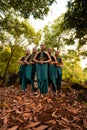 a wide shot of an Asian woman standing together in the forest while wearing a green dance costume with dead leaves Royalty Free Stock Photo