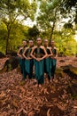 a wide shot of an Asian woman standing together in the forest while wearing a green dance costume with dead leaves Royalty Free Stock Photo