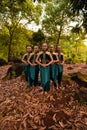 a wide shot of an Asian woman standing together in the forest while wearing a green dance costume with dead leaves Royalty Free Stock Photo