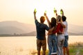 Wide shot of Back of group of friends with multi-ethnic hug together also hold bottle of drinking stand in front of sunset light