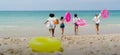 Wide shot of back of teen girls hold swimming ring and balls also run to the sea and they look happy and enjoy for holiday or