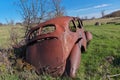 Derelict and rusty antique Vintage Car in a Farm Field on a Sunny Day