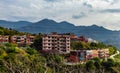 Wide shot of buildings on mountain along side road and trees with cloudy sky in the background Royalty Free Stock Photo