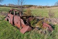 Derelict and rusty antique Vintage Car in a Farm Field on a Sunny Day