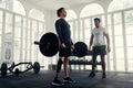 wide shot of Disabled athlete weightlifting with his coach in the gym. Man with prosthetic leg being coached by his