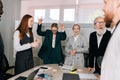 Wide shot of diverse multiracial team of happy excited business people standing around office table, celebrating launch Royalty Free Stock Photo