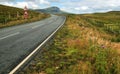 Wide shot of empty road, curve, bumps and reduce speed now sign Royalty Free Stock Photo