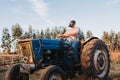 Wide shot of a farmer man with the plague mask on, driving an old tractor in the middle of his farmland. Royalty Free Stock Photo