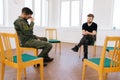 Wide shot of group of male veterans in camouflage uniform talking sitting in circle during PTSD group therapy session