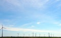 Wide shot of a group of wind turbines on a field in broad daylight