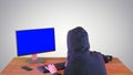 Hacker in hood cracking code using pc on gradient background. Royalty Free Stock Photo
