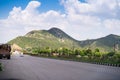 Wide shot of indian highway with trucks, cars, bikes, motorcycle and more on a wide asphalt road with green plants