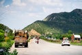 Wide shot of indian highway with trucks parked on side of road, cars, bikes, motorcycle and more on a wide asphalt road