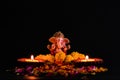 Wide shot of lord ganesha statue with flowers and two shining lamp on black background. religious and faith concept
