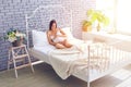 Loving woman touching her pregnant belly on bed