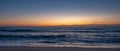 Wide shot over beach at dusk, parallel to shoreline with blue orange gradient sky Royalty Free Stock Photo