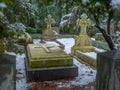 Wide shot of a part of a cemetery with tombstones of different shapes and sizes in winter