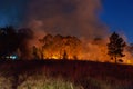 Wide shot of raging wildfire grassfire with emergency vehicle lights in background. Inspiration image for bushfire warning, summer Royalty Free Stock Photo