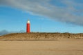 Wide shot of a red lighthouse in dunes of texel national park in netherlands