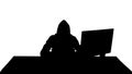 Silhouette Hooded hacker using laptop and smartphone.