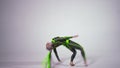 Wide shot slim woman in dazzling costume doing front handspring in slow motion at white background. Artistic flexible