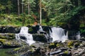 Wide shot of small cascade falls flowing down a trail surrounded by trees and green plants Royalty Free Stock Photo