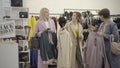 Wide shot of three confident shoppers choosing pricey clothes in shop during Black Friday sales. Portrait of smiling