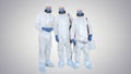 Three disinfectors walk in holding the disinfectant in their hands on gradient background.