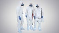 Three disinfectors walk in holding the disinfectant in their hands on gradient background.