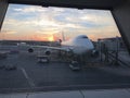 Wide shot of a white plane parked in an airplane apron near jet bridges during sunset
