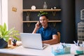 A wide shot of a young businessman taking a call at his desk in a trendy office Royalty Free Stock Photo