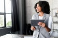 With a wide smile, an African-American businesswoman interacts with her digital tablet