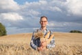 Wide smiling farmer or baker with baguettes in rye, wheat field