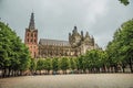 Wide square with cobblestone and trees in front of St. John`s Cathedral in a cloudy day at s-Hertogenbosch. Royalty Free Stock Photo