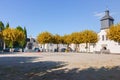 Wide square in medieval village in France. Local square with yellow trees and open church. Beautiful small square on sunny day.