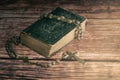 Wide studio shot of very old, vintage Holy Bible with lots of ornaments on the cover and yellow pages and old rosary on