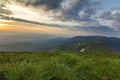 Wide summer mountain view at sunrise. Glowing orange sun raising