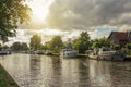 Wide tree-lined canal with houses and boat moored on its bank on sunset at Weesp.