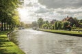 Wide tree-lined canal with houses and boats and shine of sunset reflected in water at Weesp. Royalty Free Stock Photo