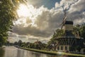 Wide tree-lined canal with windmill and boats and shine of sunset reflected in water at Weesp. Royalty Free Stock Photo