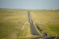 A wide undulating highway is flanked by beautiful yellow prairie