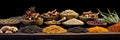 Wide variety spices and herbs on background of black table, with empty space for text or label. Spices and herbs for cooking.