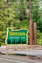 Wide vertical image of Oregon welcomes you sign on Redwood Highway with puddle after rain Royalty Free Stock Photo