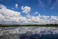 A wide view of cloudy white clouds floating above a flooded rice field Royalty Free Stock Photo