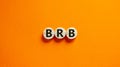 Wide view image of BRB abbreviation spelled on wooden circles. Placed over beautiful orange background, copy space. Business