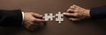 Wide view image of businessman and businesswoman hands joining two blank matching puzzle pieces Royalty Free Stock Photo